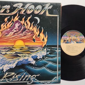 May include: Vintage vinyl record album by Dr. Hook titled "Rising." The album cover features a sunset scene with flames, waves, and the band's name. The record is black with a label featuring the band's name and song titles.