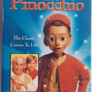 May include: DVD cover for the movie "The Adventures of Pinocchio" featuring a puppet version of Pinocchio wearing a red jacket and a red hat. The cover also features a photo of Martin Landau and Jonathan Taylor Thomas.