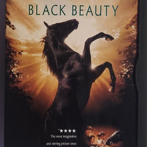 May include: DVD case for the movie "Black Beauty" featuring a black horse rearing up against a sunset backdrop. The Warner Bros. and Family Entertainment logos are at the top, with the movie title in large, green letters. The DVD case also includes a quote.