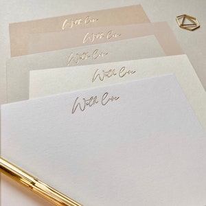 May include: Stack of five blank note cards with a gold foil inscription of "With Love" on each card. The cards are arranged in a graduated size order, with the largest card on the bottom and the smallest card on top.