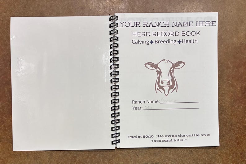 May include: A white spiral-bound herd record book featuring a brown cow illustration and text that reads: YOUR RANCH NAME HERE, HERD RECORD BOOK, Calving, Breeding, Health, Ranch Name, Year, and Psalm 50:10 He owns the cattle on a thousand hills.