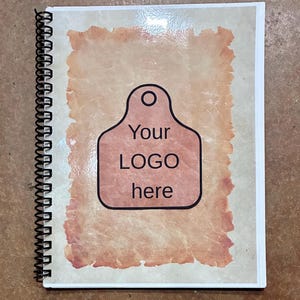 May include: A spiral-bound notebook with a light beige cover featuring a central rectangular graphic with torn edges in a reddish-brown hue. The graphic contains a black-outlined tag shape with the text Your LOGO here printed in black.
