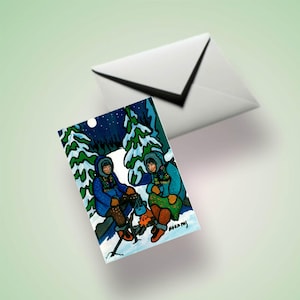 May include: Greeting card depicting a winter scene with two figures by a campfire, surrounded by snow-covered trees under a starry night sky. A white envelope is in the background.