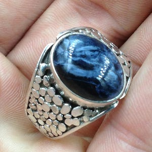 May include: A silver ring with a blue and white gemstone set in a textured band.