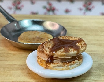 A delicious stack of miniature pancakes with chocolate sauce and a frying pan with a pancake being cooked. Perfect for you dollhouse kitchen