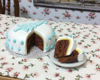 Miniature Christmas Tree Cake, with two slices removed ( loose) on plate, to reveal the marzipan, icing and rich fruit cake inside.