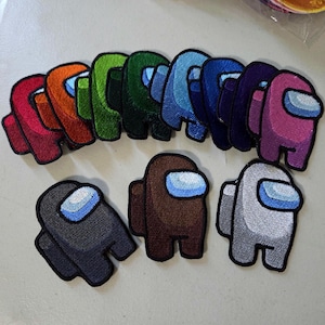 May include: A collection of twelve embroidered patches shaped like characters in various solid colors including red, orange, lime green, dark green, light blue, royal blue, navy, purple, pink, dark gray, brown, and light gray, each with a light blue visor.