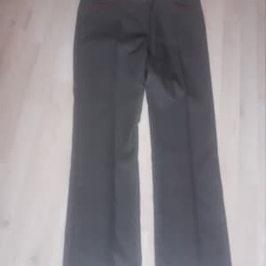 May include: A pair of dark gray pants with a red and white trim around the waistband and pockets.