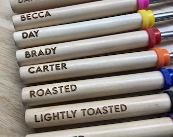May include: Nine wooden skewers with colorful plastic tips. The skewers are labeled with names like "Danny", "Becca", "Day", "Brady", "Carter", "Roasted", "Lightly Toasted", and "Charred".