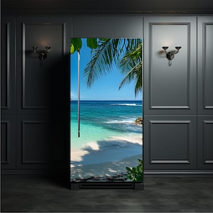 May include: A tall, rectangular refrigerator featuring a full-length photographic wrap of a tropical beach scene. The image displays a bright blue ocean, white sand, and green palm fronds hanging from the top, with a vertical silver handle.