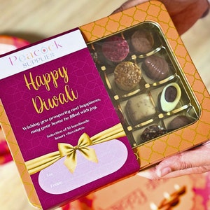 May include: A pink and gold gift box with the words "Peacock Supplies" and "Happy Diwali" on the front. The box contains a selection of 16 handmade luxury chocolates.