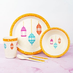 May include: A children's dinnerware set featuring a plate, bowl, cup, spoon, and fork. The set has a cream-colored base with a pattern of colorful lanterns. The rims are orange with white polka dots. The utensils are white with orange accents.