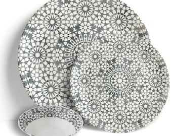 May include: A set of four ceramic dishes with a white and gray geometric starburst pattern. The set includes two large plates, a smaller plate, and a bowl. The dishes are arranged on a white background.