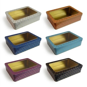 May include: A set of six rectangular metal tins with clear windows on the lids. Each tin features a gold interior and a repeating lattice pattern on the exterior in silver, copper, dark blue, light blue, purple, and black colour variations.