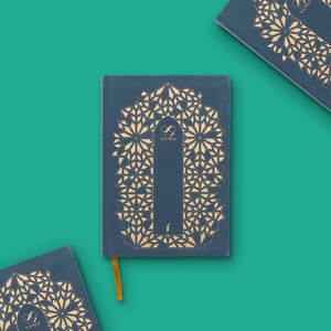 May include: A navy blue journal with a gold geometric design and the text "99 NAMES". The journal has a gold ribbon bookmark. Several journals are arranged on a teal background.