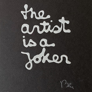 May include: Black artwork with the white text "the artist is a joker." The text is in a handwritten style. A signature is in the bottom right corner. The artwork is on a black background.