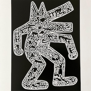 May include: Black and white print of Keith Haring's "Dog" from 1985. The artwork features a stylized dog-like figure with a TV in its torso, filled with intricate patterns and shapes. The dog is outlined in white against a black background.