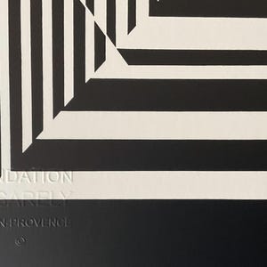 May include: Black and white abstract geometric art print with a white background and black lines. The print features a repeating pattern of squares and rectangles that create a sense of depth and perspective. The print is signed "Fondation Vasarely Aix-en-Provence".