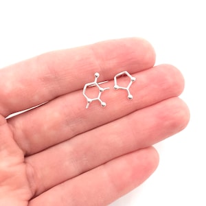 May include: A pair of silver earrings shaped like the chemical structure of caffeine.