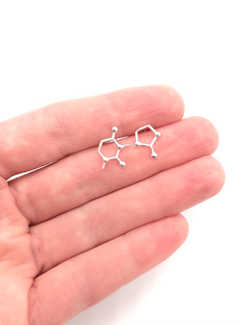 May include: A pair of silver earrings shaped like the chemical structure of caffeine.
