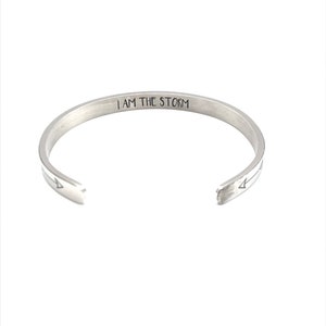 May include: A silver bangle bracelet with the words "I AM THE STORM" engraved on the inside.