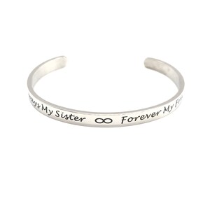 May include: Silver bangle bracelet with the inscription "Always My Sister ∞ Forever My Friend".