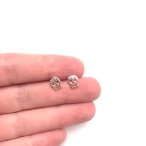 Op de afbeelding: Een paar zilveren schedel oorbel studs. De schedels zijn getextureerd en hebben een licht verweerde look.