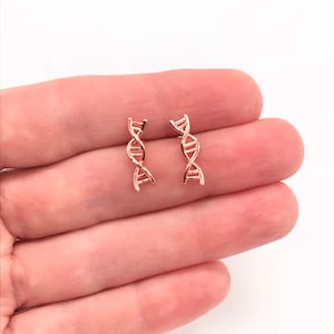 May include: A pair of rose gold DNA helix earrings. The earrings are small and delicate, and they are perfect for anyone who loves science or fashion.