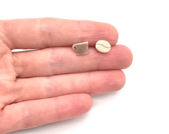 May include: A pair of gold-toned earrings featuring a coffee cup and a coffee bean design.