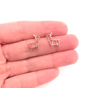 May include: A pair of silver origami deer stud earrings. The earrings are small and delicate, and they are perfect for adding a touch of whimsy to any outfit.