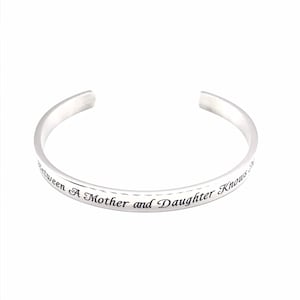 May include: Silver bangle bracelet with the inscription "Between a Mother and Daughter Knows No End".