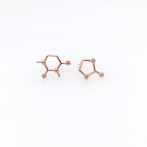 May include: A pair of rose gold earrings shaped like the chemical structure of caffeine.