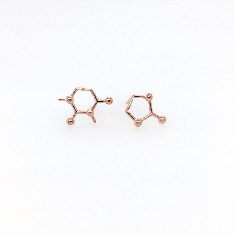 May include: A pair of rose gold earrings shaped like the chemical structure of caffeine.