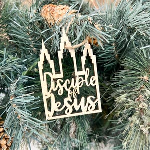 May include: Wooden Christmas ornament shaped like a temple with the text "Disciple of Jesus" in cursive.
