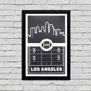 May include: Black and white print of the Los Angeles skyline with a football field and football in the center. The text "Los Angeles" is at the bottom of the print.