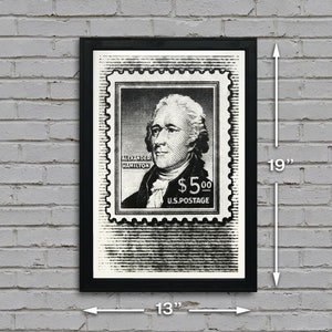 May include: Black and white print of a vintage postage stamp featuring a portrait of Alexander Hamilton with the text "Alexander Hamilton $5.00 U.S. Postage". The print is framed in a black frame and measures 13 inches wide by 19 inches tall.