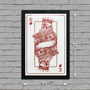 May include: A framed print of a playing card, the King of Diamonds, featuring a skull in a crown and a red and white design. The card is 13 inches wide and 19 inches tall.