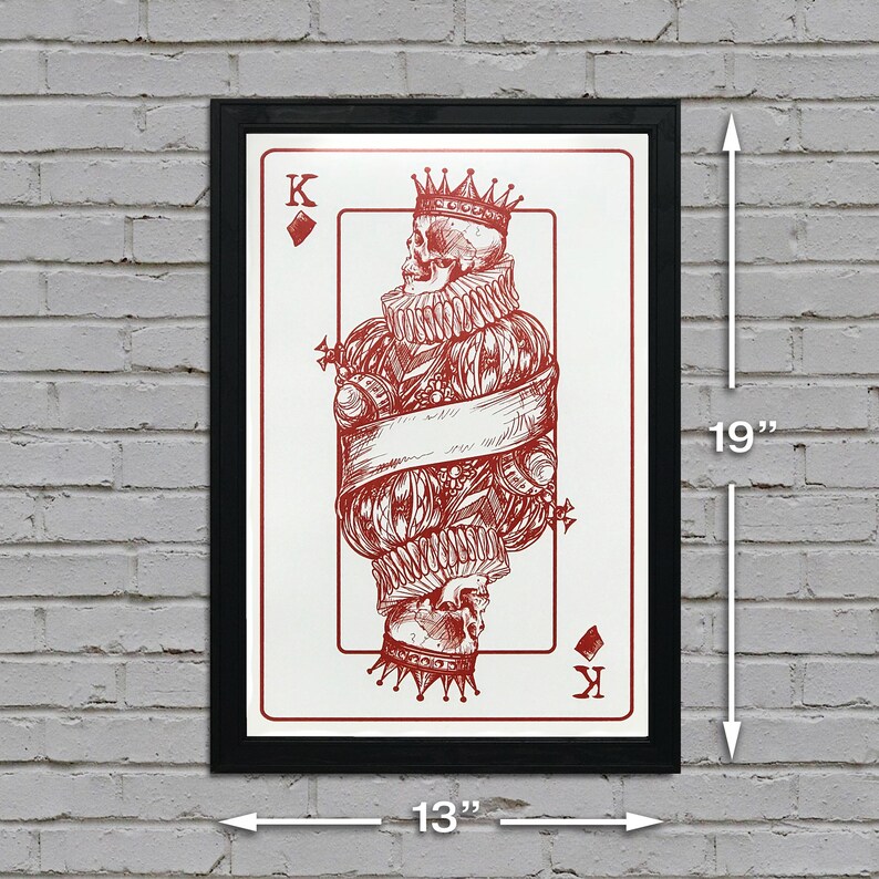 May include: A framed print of a playing card, the King of Diamonds, featuring a skull in a crown and a red and white design. The card is 13 inches wide and 19 inches tall.