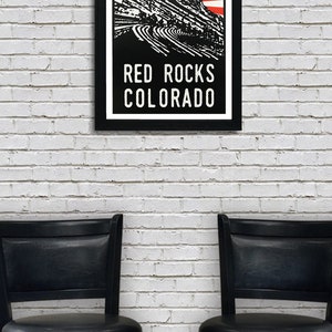 K&ouml;nnte beinhalten: Eine Schwarzwei&szlig;illustration des Red Rocks Amphitheaters in Colorado mit einem roten und wei&szlig;en Sonnenstrahl dahinter. Der Text "RED ROCKS COLORADO" befindet sich unter der Illustration.
