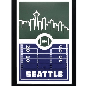 May include: A framed print with a green and blue design featuring a white silhouette of the Seattle skyline, a football, and the word "SEATTLE".
