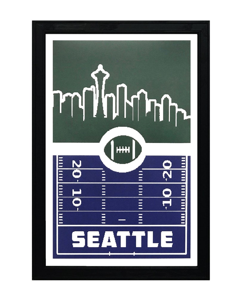 May include: A framed print with a green and blue design featuring a white silhouette of the Seattle skyline, a football, and the word "SEATTLE".
