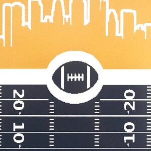May include: A black and white illustration of a football on a white circle against a yellow background. The football is centered on a black and white football field with white yard lines and the numbers '20' on either side of the field.