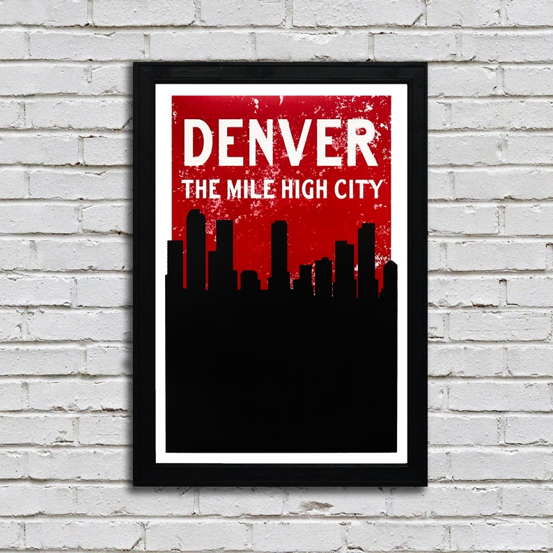 May include: Framed art print featuring the word "DENVER" above "THE MILE HIGH CITY" in white text against a distressed red background. A black silhouette of a city skyline is below the text, set against a black background.