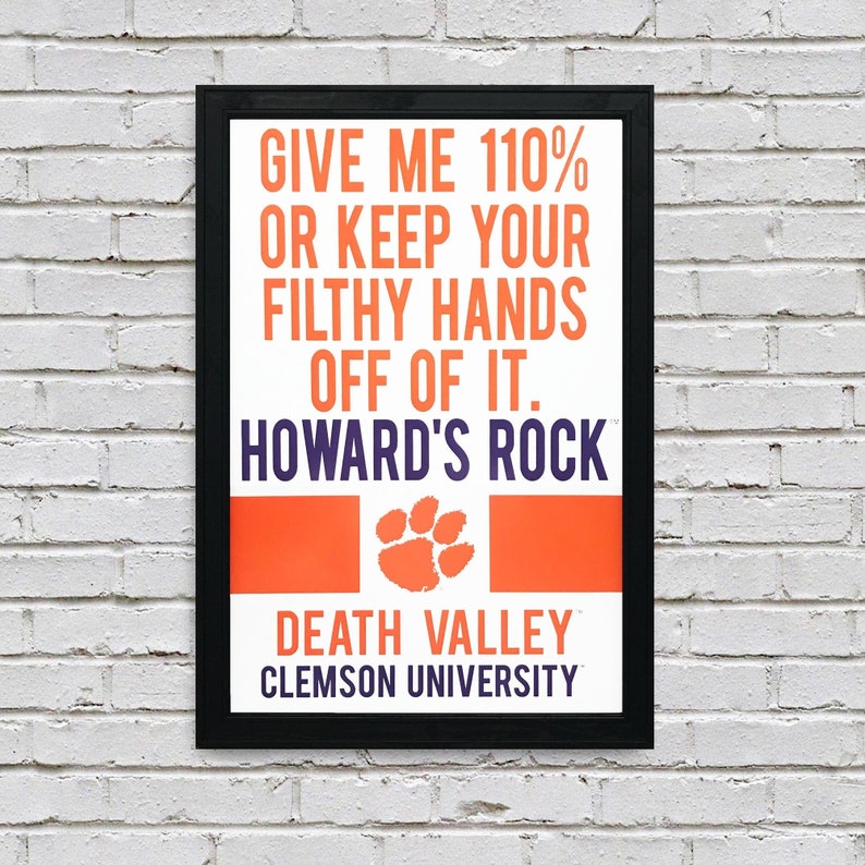 May include: A black framed poster with an orange and white background. The poster says "Give me 110% or keep your filthy hands off of it. Howard's Rock. Death Valley. Clemson University." with a purple paw print in the center.