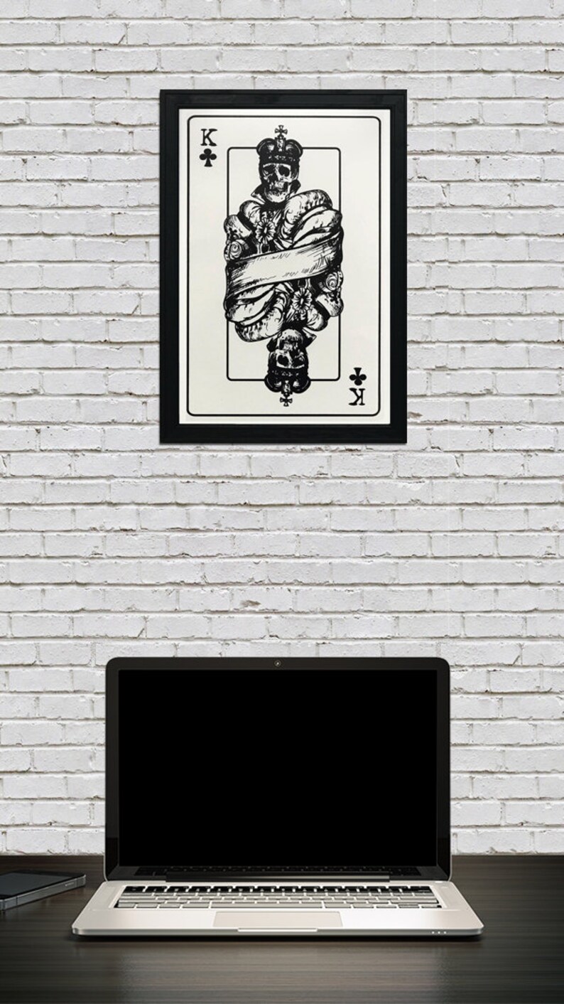 May include: Black and white illustration of the King of Clubs playing card. The King is a skeleton wearing a crown and is bound by a ribbon. The card is framed in black.
