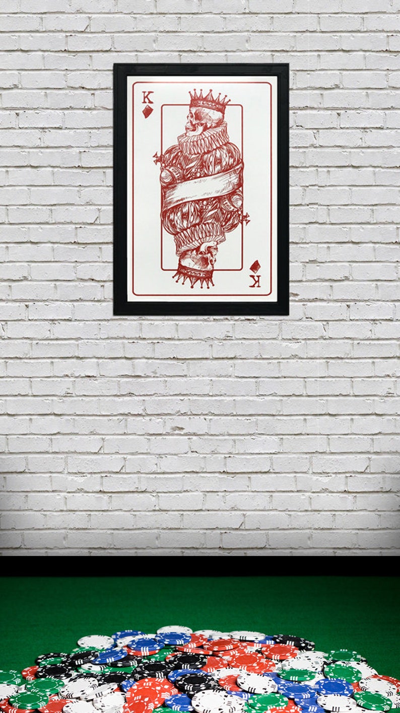 May include: A framed illustration of the King of Diamonds playing card. The card features a red skull wearing a crown and a ruff collar. The card is set against a white brick wall with a pile of poker chips in the foreground.