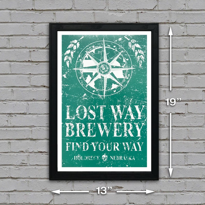 May include: A framed poster with a distressed green background and white text. The poster features a compass with a white star and the text "Lost Way Brewery Find Your Way" with the location "Hildreth, Nebraska". The poster is 13 inches wide and 19 inches tall.