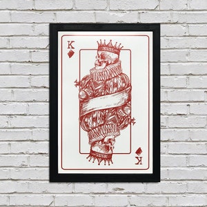 May include: A framed print of a playing card featuring a king of spades. The king is depicted as a skeleton wearing a crown and a robe. The card is in a black frame.