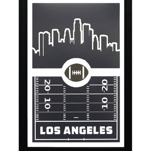 May include: Black and white framed print of a football field with a Los Angeles skyline and the text "LOS ANGELES" at the bottom.