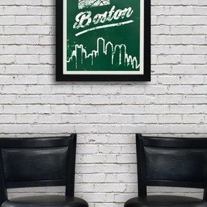 May include: A framed poster with a green background and white text that says "Boston". A basketball is above the text and a white silhouette of the Boston skyline is below the text. The poster is hanging on a white brick wall between two black bar stools.